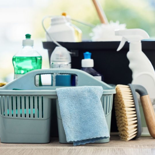 All cleaning items like all purpose cleaner spray bottle, utility basket, brush, cleaning towel, bucket, mops kept together at a place.