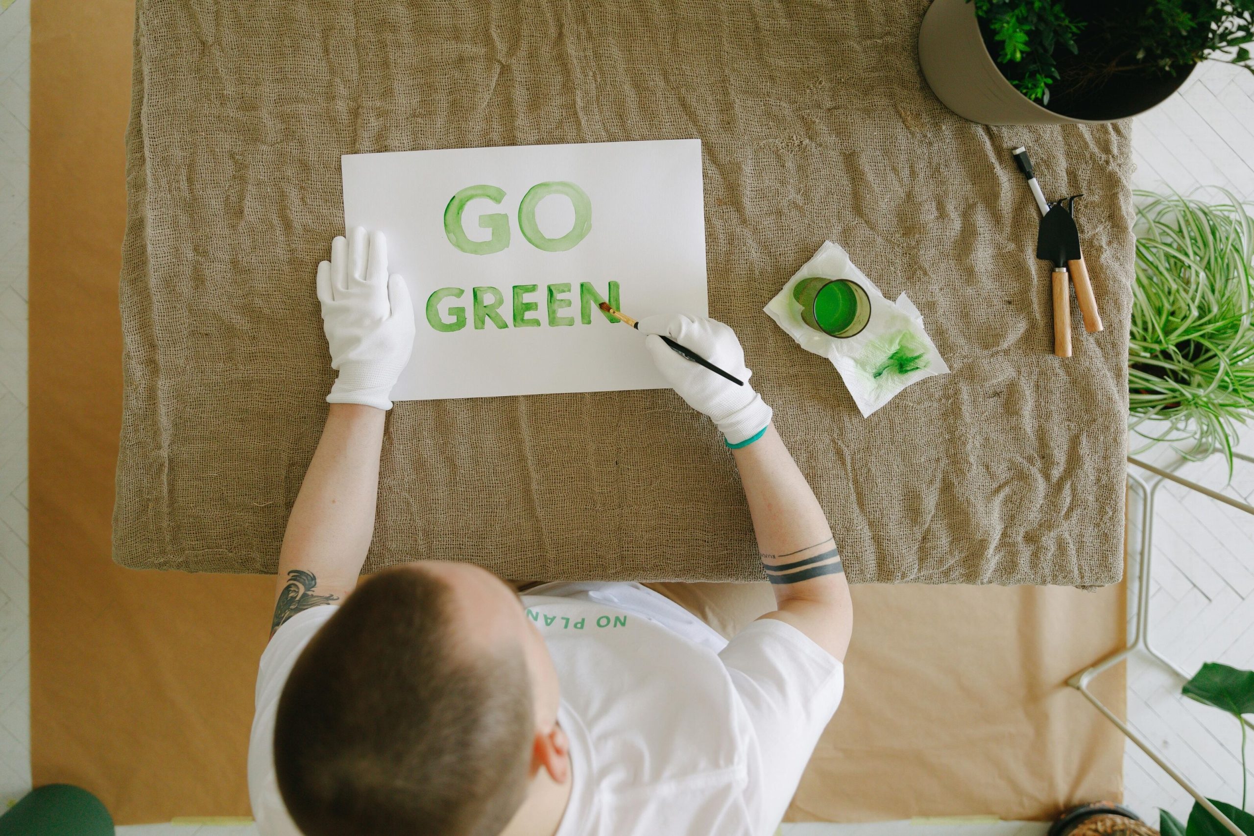 A man writing "GO GREEN" on a white paper with green Eco-Friendly Paint.