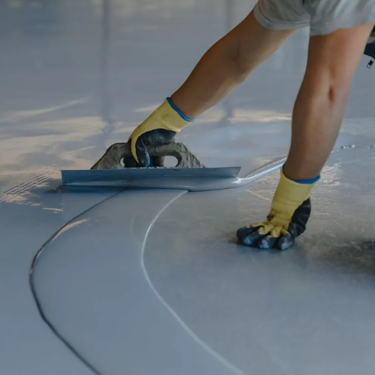 Worker applying protective floor coating in an industrial facility to enhance safety and hygiene.