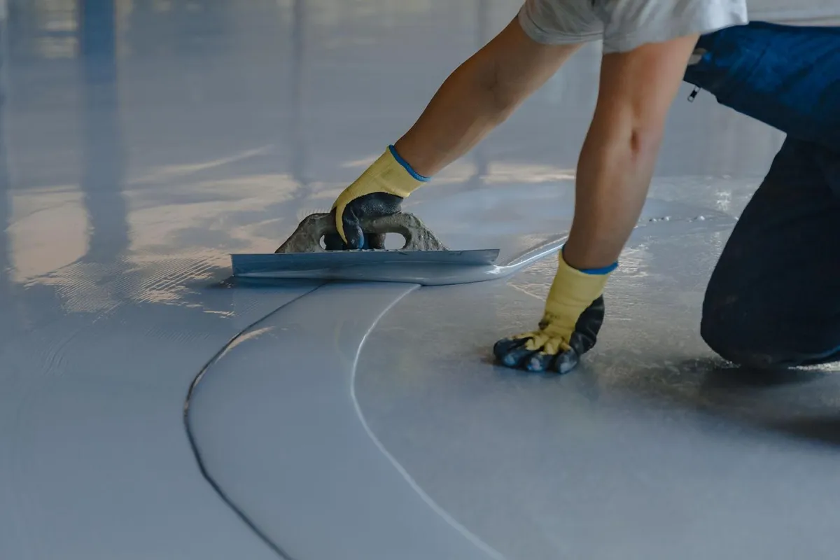 Worker applying protective floor coating in an industrial facility to enhance safety and hygiene.