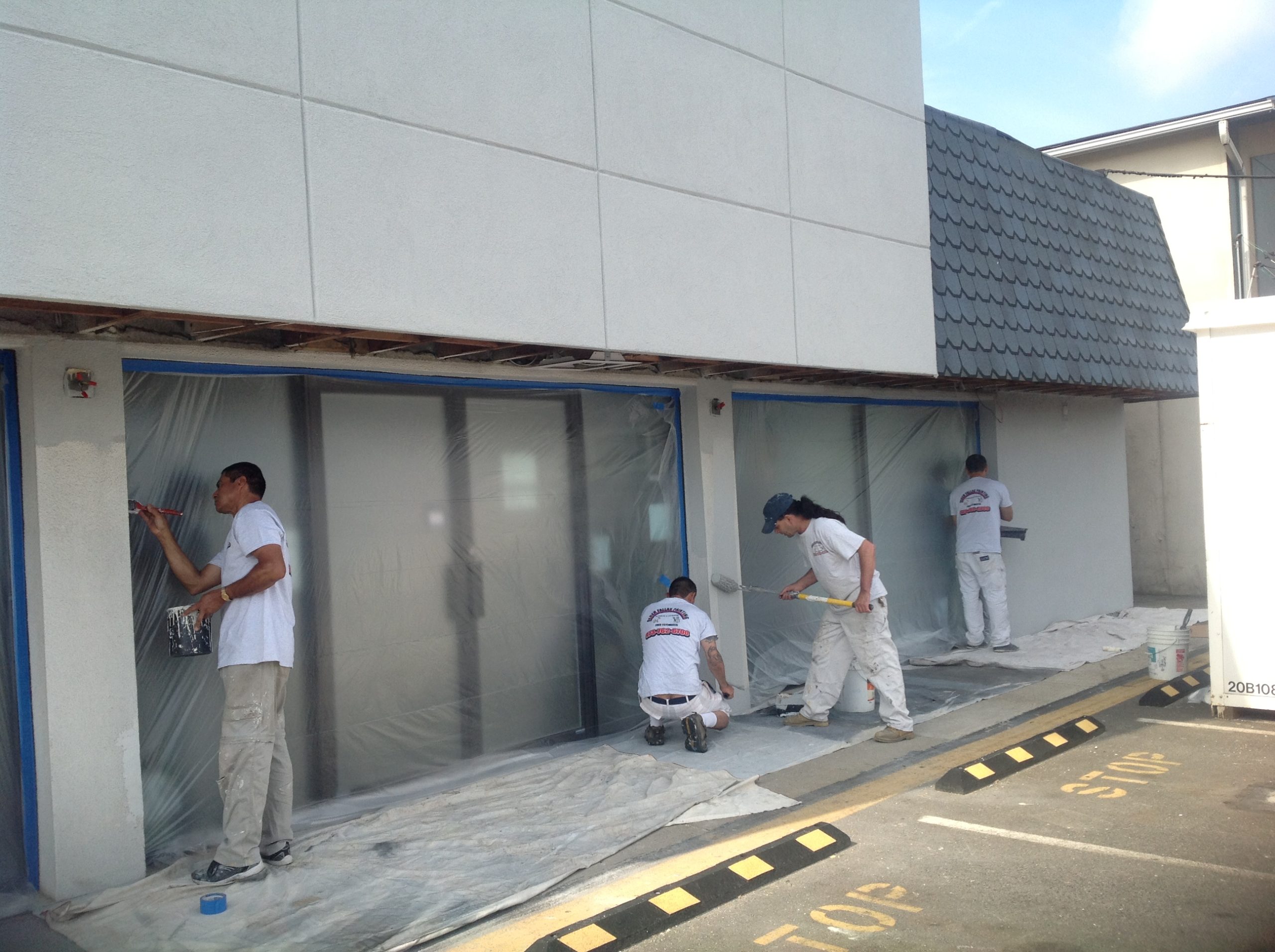 Team of painters applying waterproof paint on exterior walls, following best practices for long-lasting protection with Berger Paint.