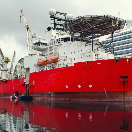 Large red ship docked at harbor, highlighting the importance of anti-fouling paint for protecting vessels in Singapore waters.